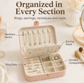 Open pink travel jewellery box showing necklace hooks, earring panel, ring slots and divided compartments